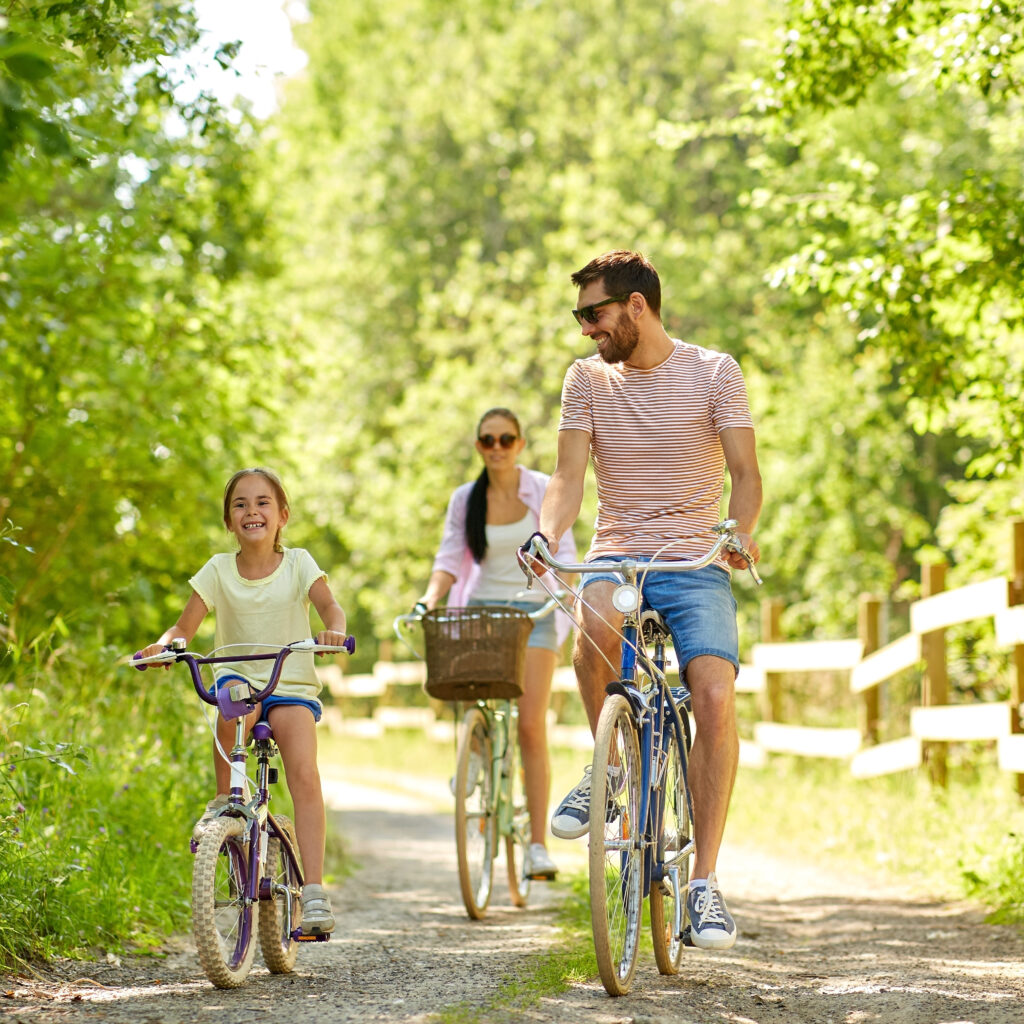 happy family riding bicycles in summer park