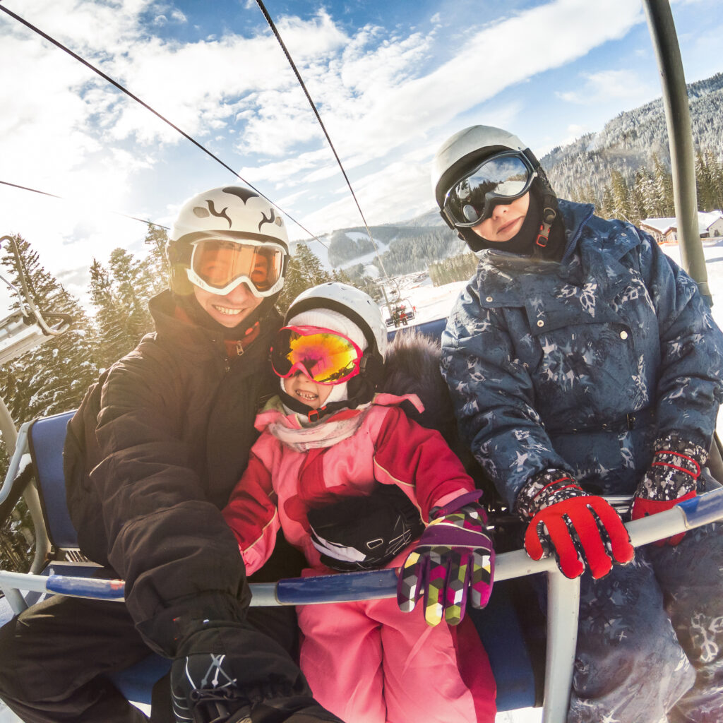 happy smiling family skiers on ski lift making selfie