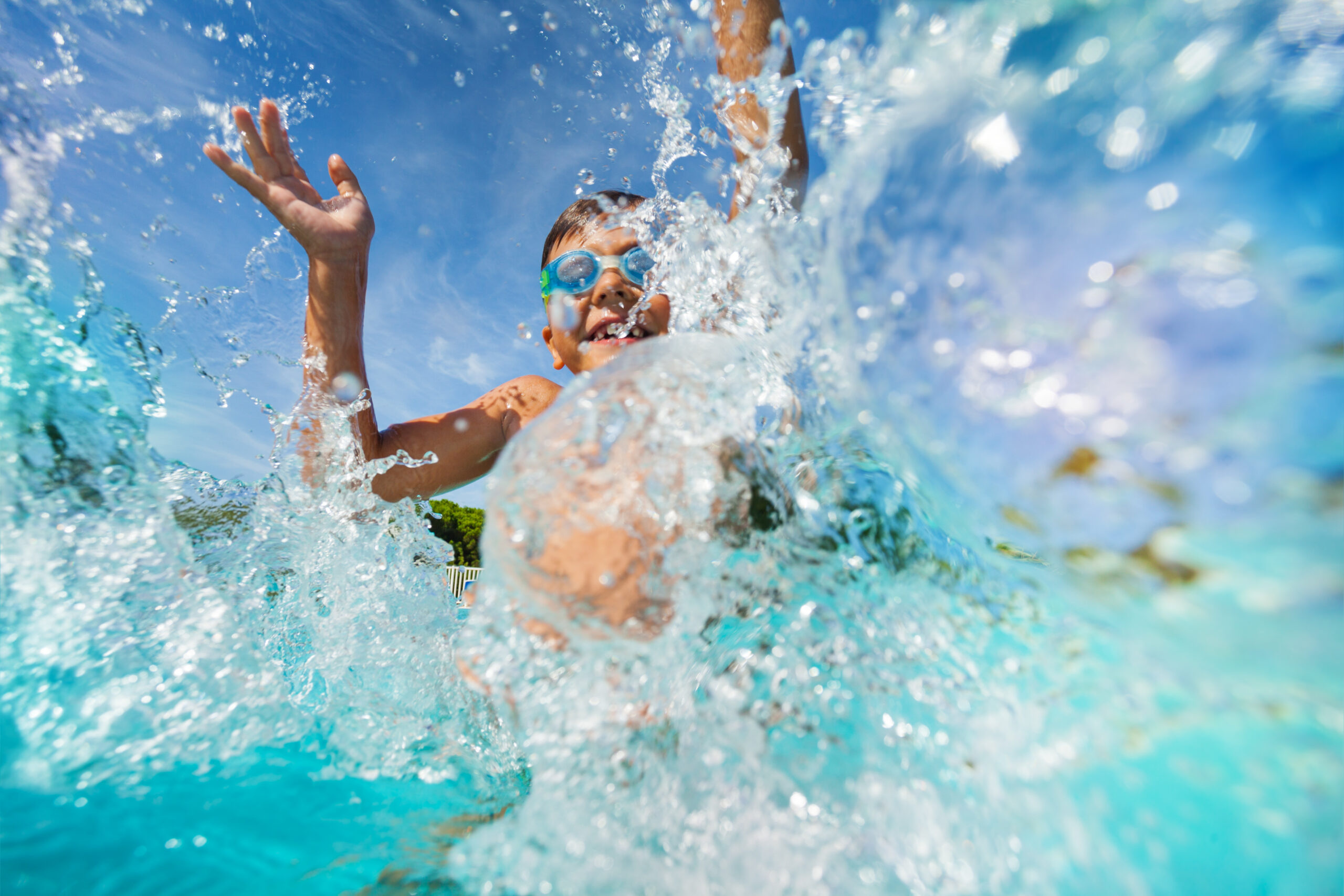 happy boy playing and splashing in swimming pool